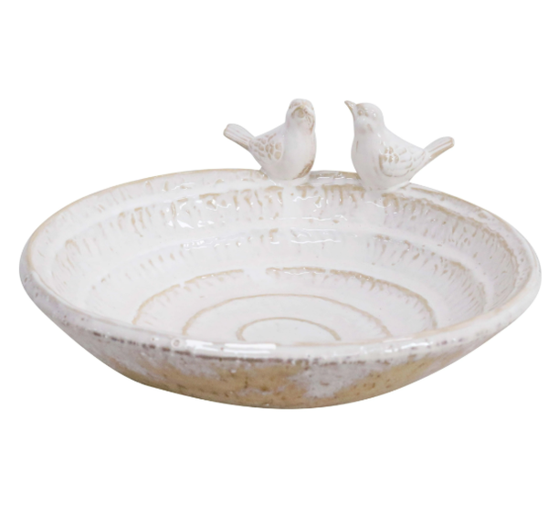 A shallow, rounded ceramic bird bath with a smooth, neutral-coloured finish. The edge of the bath is slightly curved, with two small, sculpted birds perched on opposite sides.