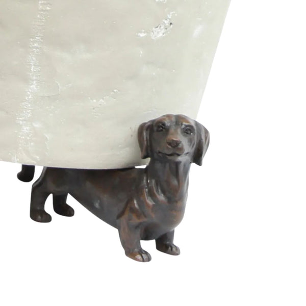 A set of three small, brown dachshund dog-shaped resin figurines. Each figurine has a different pose, and they are designed to be placed under a pot to elevate it.