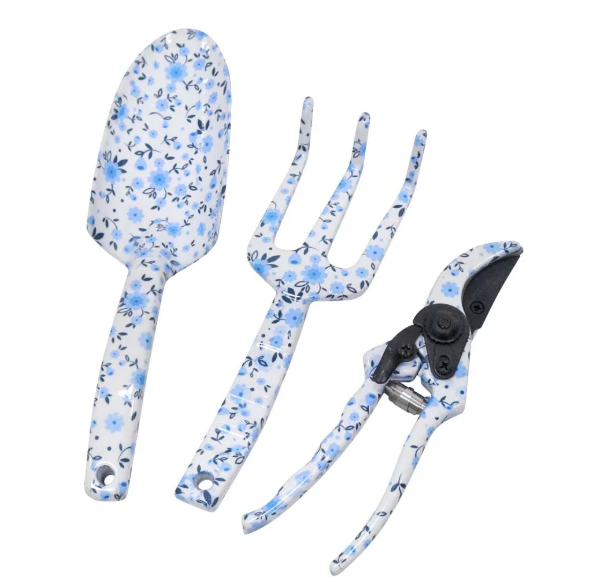 A three-piece garden tool set, including a small trowel, a three-pronged hand fork, and a pair of secateurs. The handles of all three tools are painted white with a delicate blue floral pattern. The metal parts of the tools are silver-toned.