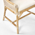 A dining chair with a frame made of light-coloured bamboo. The backrest is tall with a woven rattan insert and an arched top detail. The seat is a light, natural-coloured fabric cushion. The chair has armrests and a high back. Front Leg Detail.