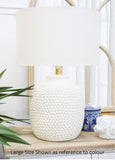 White textured table lamp on a wooden surface with a blurred background