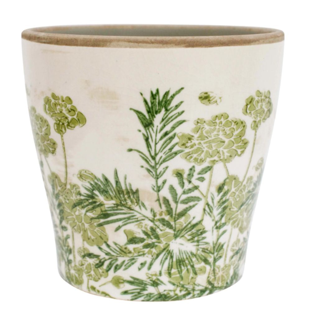 A cylindrical ceramic planter with a rustic, slightly distressed finish. The pot is a cream or off-white colour and is decorated with a muted green botanical print of leaves and flowers. The rim is a darker, earthy tone.