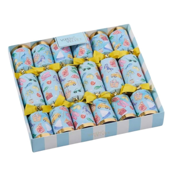 A set of La Dolce Vita Seaside Crackers in bright coastal prints, tied with yellow bows, displayed in a striped gift box. Includes seaside-themed gifts, mottos, and paper crowns.