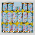 A set of La Dolce Vita Seaside Crackers in bright coastal prints, tied with yellow bows, displayed in a striped gift box. Includes seaside-themed gifts, mottos, and paper crowns.