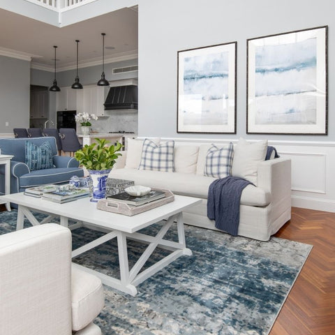 White Hamptons style coffee table styled in a coastal living room with soft blue rug, neutral sofa, and layered cushions.