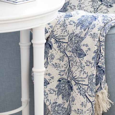 Blue and white floral Hamptons style throw draped over armchair beside white side table