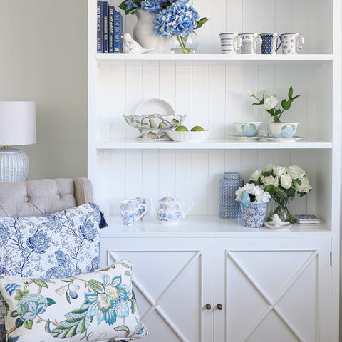 White Hamptons style bookcase styled with blue and white ceramics, books and coastal décor in a light filled interior