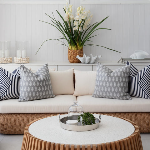 Outdoor wicker sofa with neutral cushions and blue patterned pillows styled on a Hamptons style patio setting