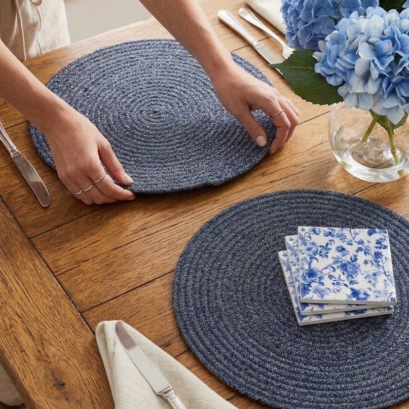 Blue woven coastal placemats styled on a timber dining table with hydrangeas and Hamptons-inspired table décor