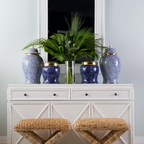 White furniture in a Hamptons-style interior featuring a white buffet cabinet, decorative mirror, blue and white ceramics, woven stools and coastal home décor styling.