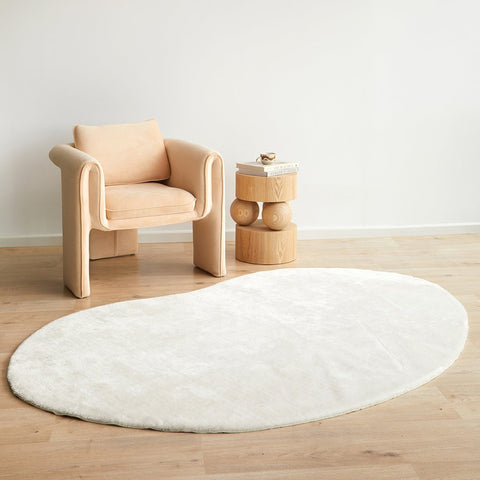 Snow White jelly bean shaped rug styled in a modern coastal interior with armchair and timber side table
