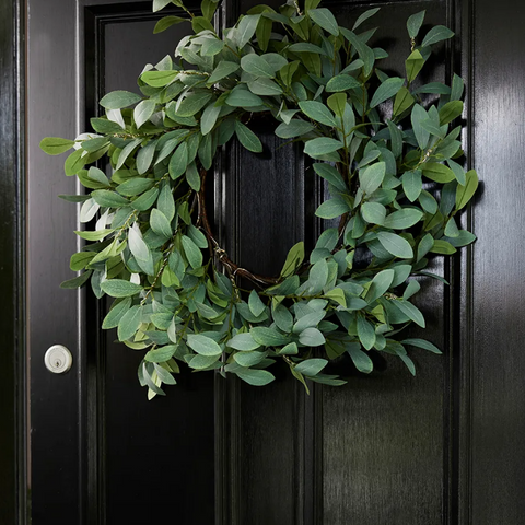 Large illuminated olive wreath with warm LED lights, hanging on a front door.