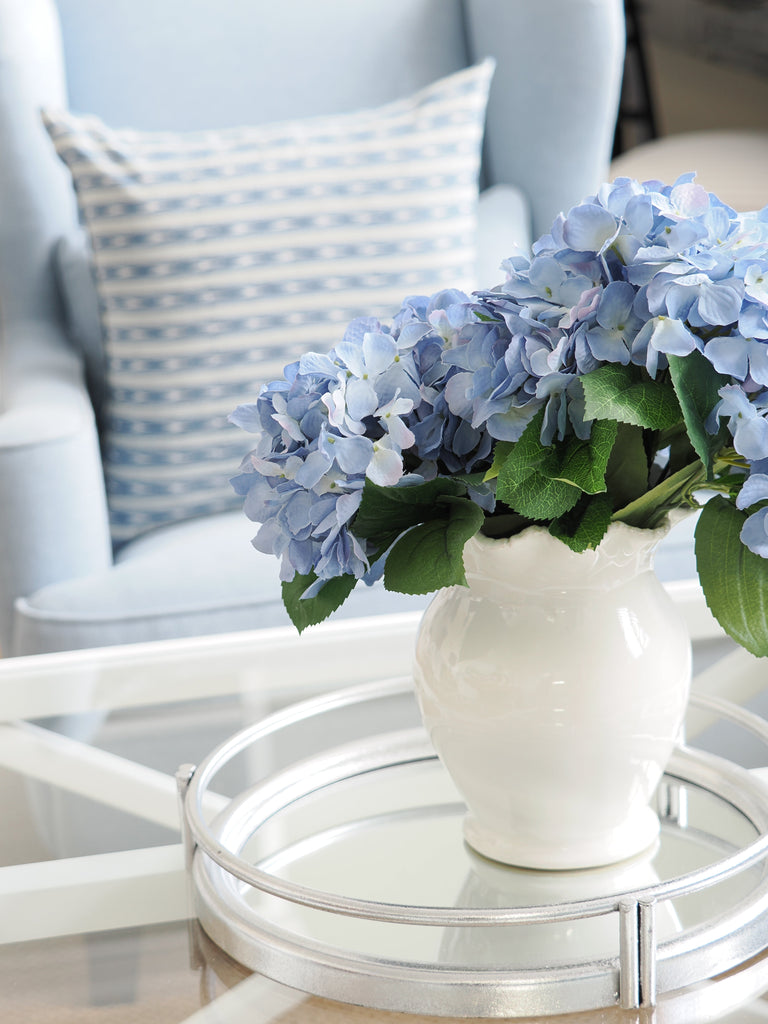 Hamptons style mirror tray with white ceramic vase and blue hydrangeas styled on coffee table in coastal living room