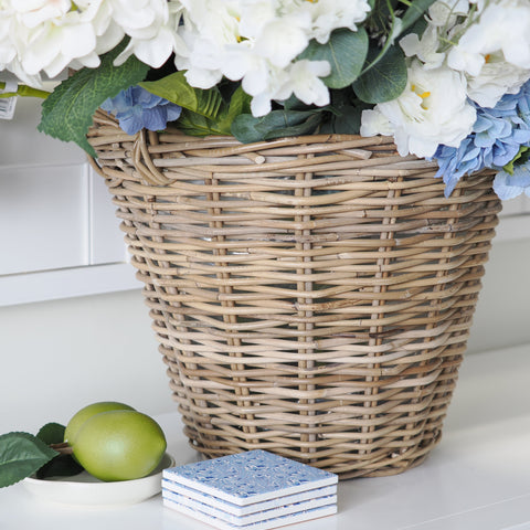 Blue patterned ceramic coasters styled on a shelf with a wicker basket and decorative green fruit in a Hamptons-style home.