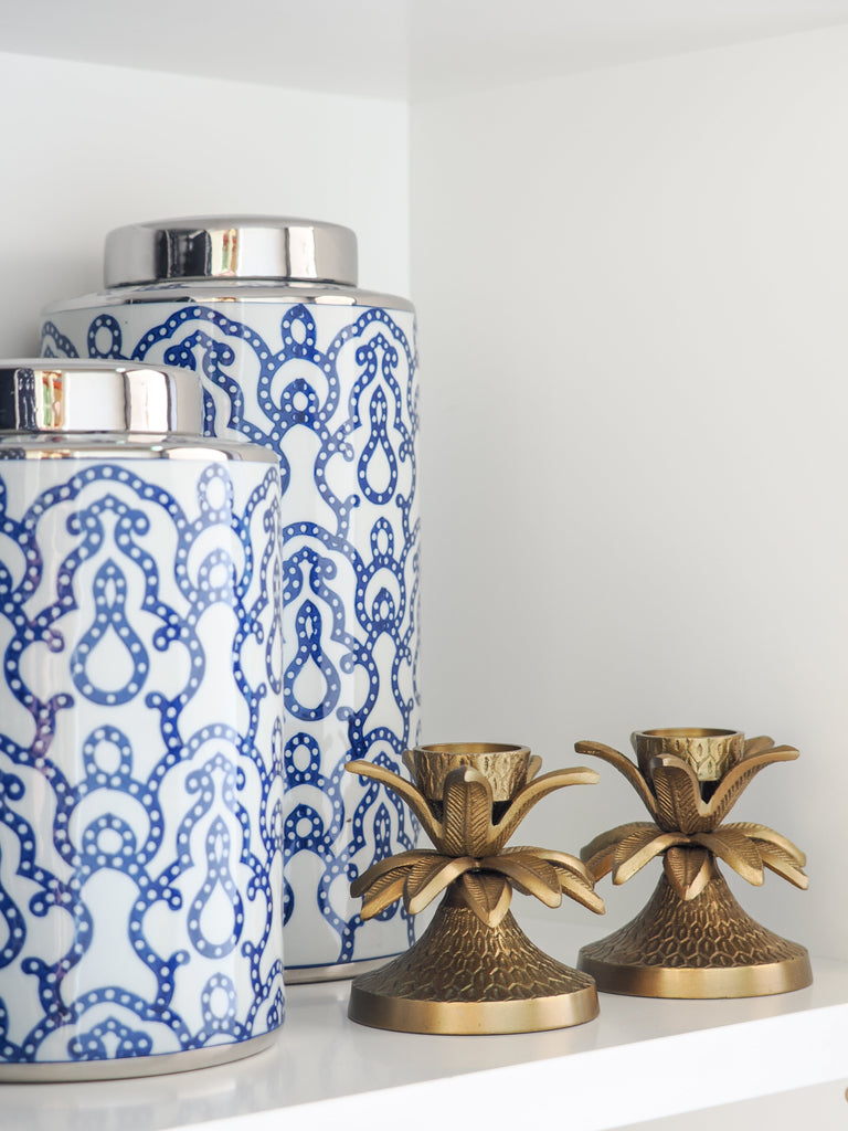 White magnolia stem in a glass vase styled with decorative coastal bird ornaments and home décor accessories on a console table