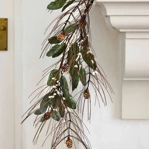 Artificial Christmas garland with pine branches, eucalyptus leaves and berries draped over mantel in neutral coastal style home