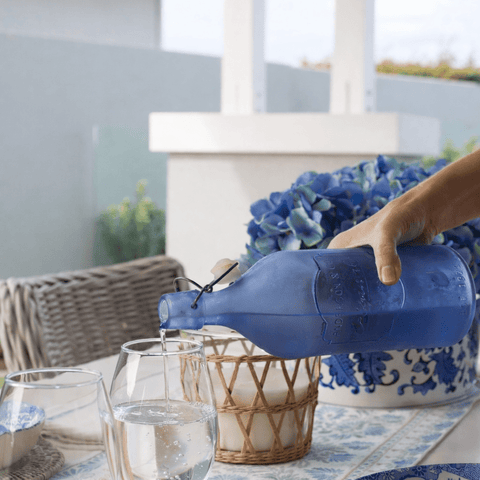 Coastal outdoor table styling with blue and white tableware, woven placemats, floral table runner and relaxed Hamptons entertaining setting