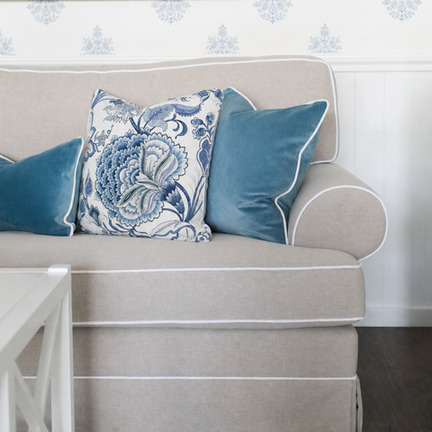 Decorative coastal cushions in blue and neutral tones styled on a sofa with soft textures and Hamptons-inspired interior