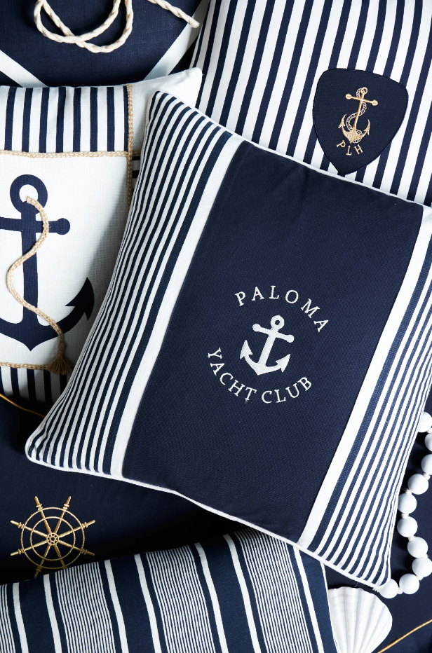 Navy blue nautical cushions with anchor motifs and striped detailing styled in a Hamptons-style interior.