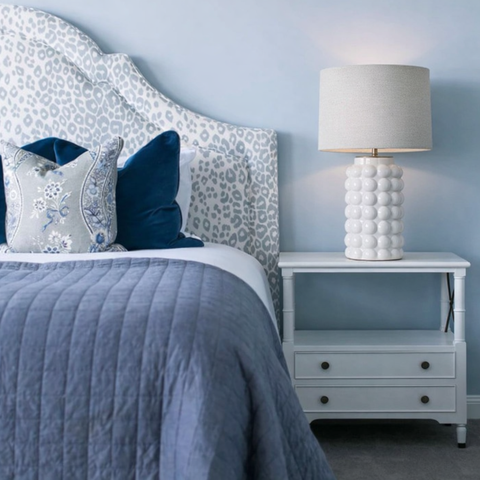 White bubble ceramic table lamp on blue bedside table in coastal bedroom.
