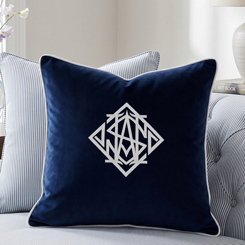 Navy velvet cushion with white geometric monogram on striped sofa in a Hamptons style living room