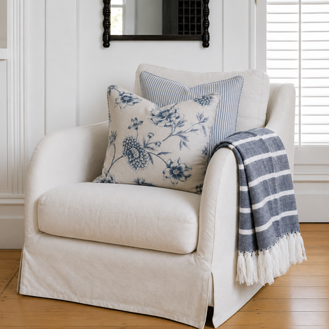 White coastal armchair styled with blue floral cushions and striped throw for relaxed autumn home styling