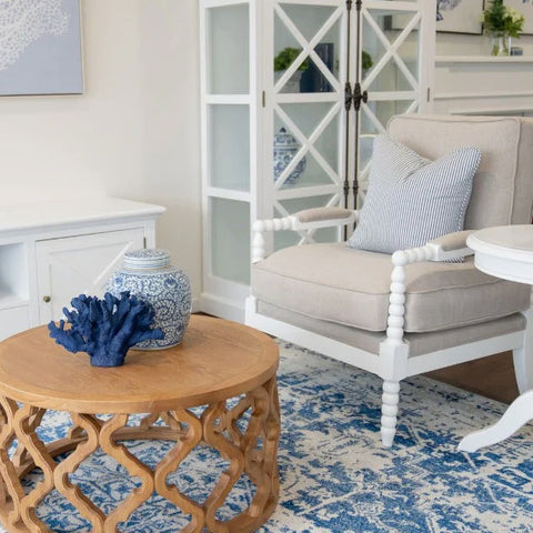 Blue and white patterned rug styled in a Hamptons living room with natural timber and coastal decor