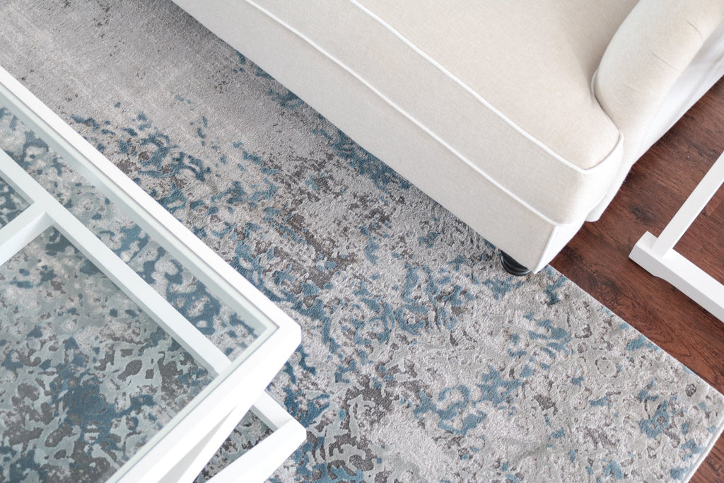 Rectangular blue and neutral patterned rug styled under sofa and coffee table in a coastal living room