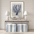 Designer Boys Coral SPLENDOUR Indigo XII artwork styled above a console with white lamps and blue striped stools in a Hamptons coastal interior.