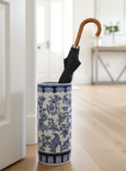 Blue and white ceramic aviary patterned umbrella stand holding a black umbrella in a hallway