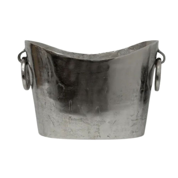 Antique-style silver wine bucket with large ring handles, featuring a curved rim and vintage finish, styled with champagne bottles on a dining table.