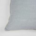 Beach blue square cushion with soft fabric texture and piped edging, styled on a white background. Close up of corner.