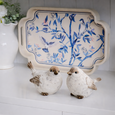 Decorative birds and a tray with floral design on a white surface