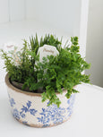 Small blue and white floral wide pot styled with fresh greenery beside a Hamptons garden book on a white console