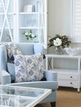 Bluebell Bloom blue and white floral cushion styled on armchair with matching throw in coastal living room