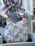 Bluebell Bloom blue and white floral cushion styled on armchair with matching throw in coastal living room