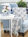 Bluebell Bloom blue and white floral cotton throw draped over a sofa beside a white side table
