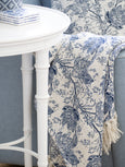 Bluebell Bloom blue and white floral cotton throw draped over a sofa beside a white side table