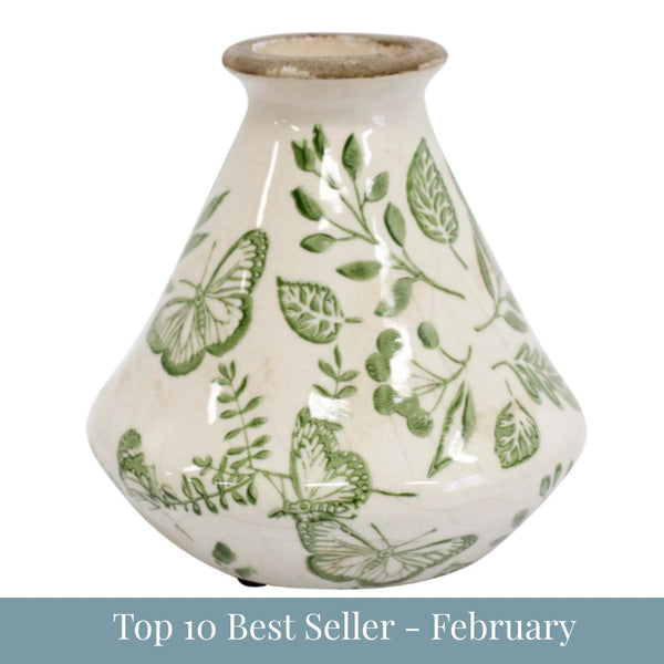 Small ceramic bud vase with green butterfly and foliage design on an off-white base, 12x12x12cm.