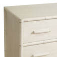 A chest of drawers with three full-width drawers. The frame and drawer faces are a distressed white wash colour, and the frame corners and drawer separators have subtle raised detailing that resembles bamboo poles. The drawers have long, recessed pull handles. Top corner detail. 