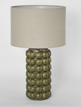 Green ceramic table lamp with raised spherical base and linen shade on white background