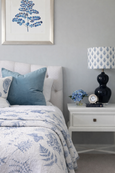 A reversible, quilted cotton coverlet with a blue and white botanical print of ferns and butterflies. One side is a white background with a blue print, and the reverse is a solid light blue with a white print.