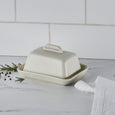 Cream stoneware butter dish on marble kitchen bench with herbs