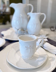 White stoneware jug with raised dragonfly detail and curved handle, styled in a coastal Hamptons interior.