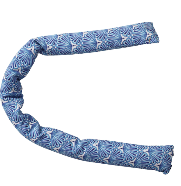 A long, rounded draught stopper made from a light-coloured fabric with a repeating pattern of stylized fan shells in various shades of blue. The stopper is shown bent into a U-shape.
