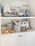 Duck captain and sailor figurines styled on a shelf in a coastal living space, wearing soft blue nautical uniforms.