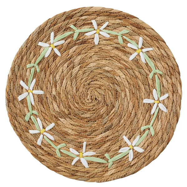 Round natural seagrass placemat with stitched white flowers and green leaf detailing.