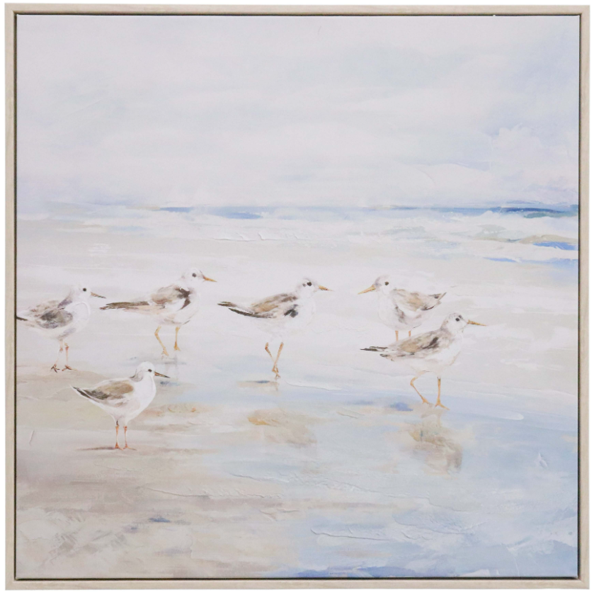 Framed coastal wall art featuring sandpipers walking along the shoreline, painted in soothing neutral tones with a light wooden frame.