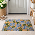 Hydrangea-patterned coir doormat placed directly in front of a soft grey front door, styled with a woven basket of white hydrangeas, neutral slip-on shoes and a wooden bench on light herringbone tile flooring.