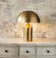 Jacaranda Table Lamp Brass sitting on a console with a brick wall behind